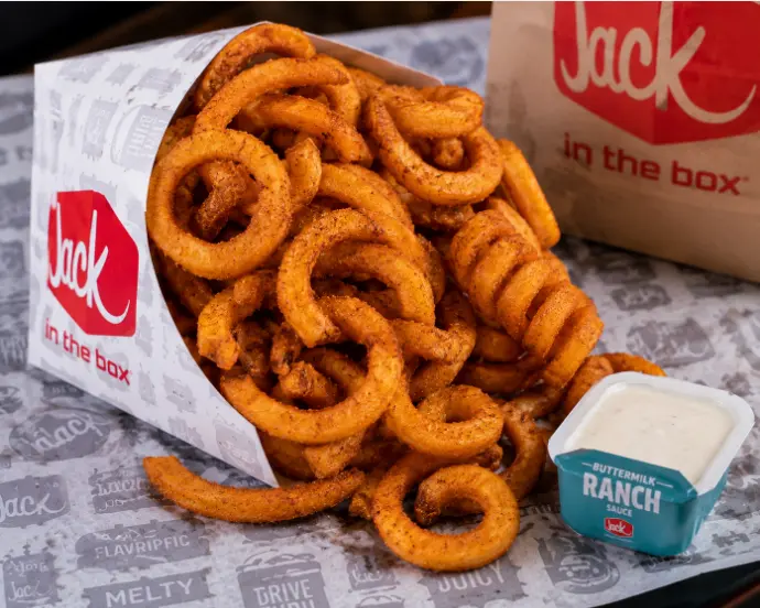 Seasoned curly fries in a Jack in the Box container with ranch dipping cup